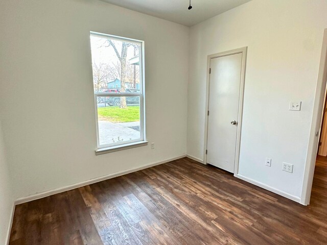 unfurnished room with dark wood-type flooring