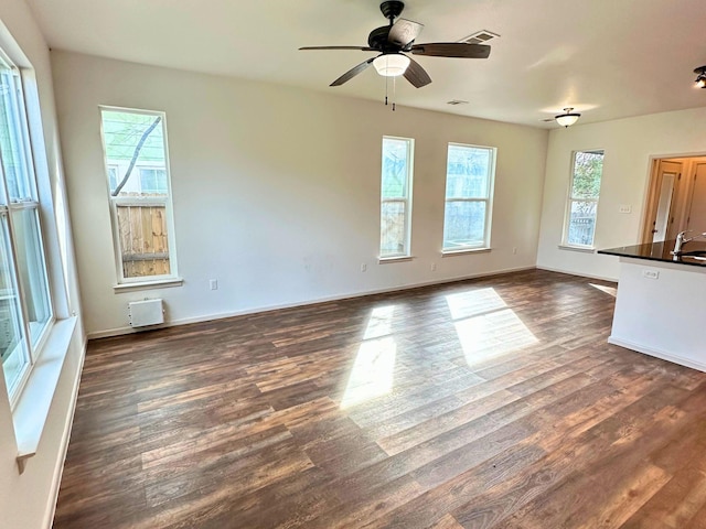 unfurnished living room with ceiling fan, sink, and dark hardwood / wood-style flooring