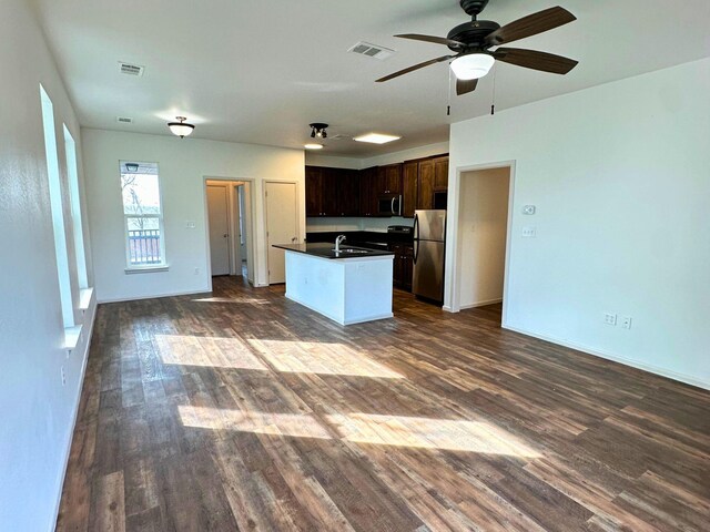 kitchen featuring dark wood-type flooring, dark brown cabinetry, sink, stainless steel appliances, and a kitchen island with sink