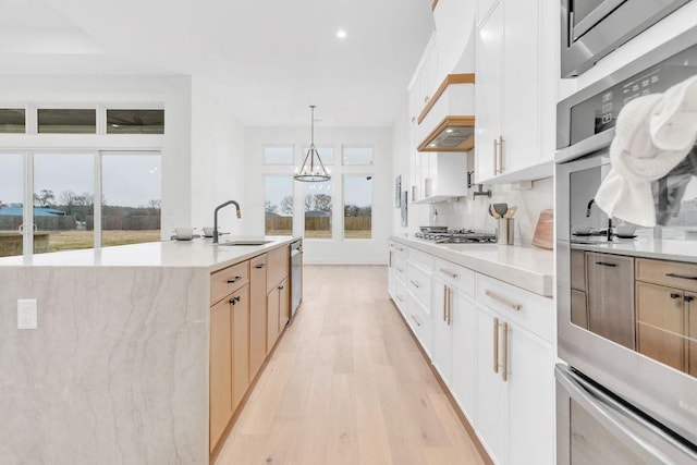 kitchen with sink, white cabinetry, hanging light fixtures, appliances with stainless steel finishes, and decorative backsplash