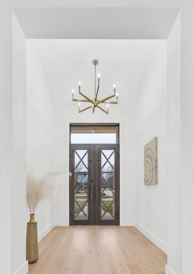 entryway featuring wood-type flooring, lofted ceiling, and french doors