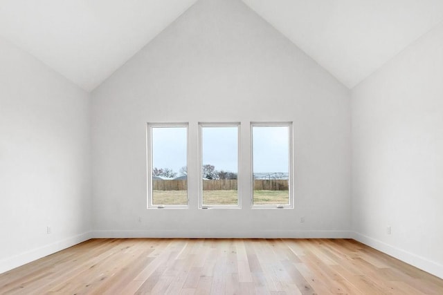 empty room featuring high vaulted ceiling and light wood-type flooring