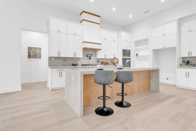 kitchen with white cabinetry, appliances with stainless steel finishes, a kitchen bar, and a center island with sink