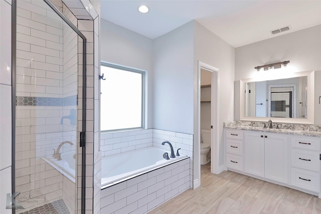 full bathroom featuring vanity, toilet, separate shower and tub, and wood-type flooring