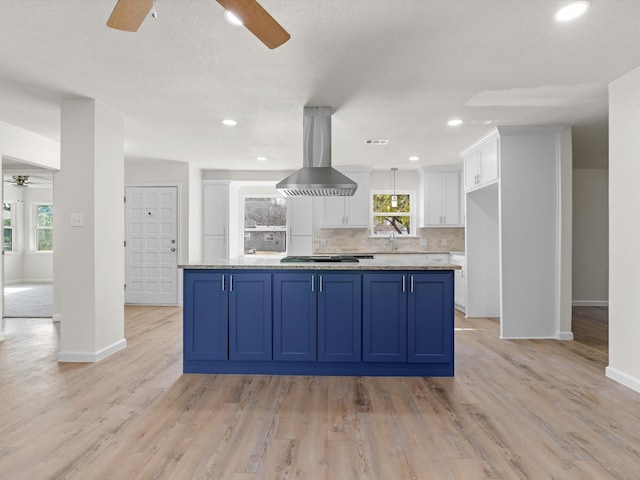 kitchen with white cabinetry, a kitchen island, blue cabinetry, and island exhaust hood