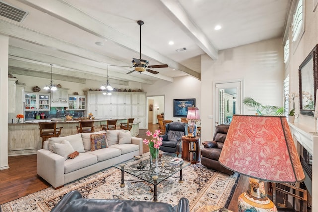 living area featuring visible vents, a ceiling fan, wood finished floors, and beam ceiling