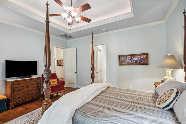 bedroom featuring visible vents, crown molding, wood finished floors, ceiling fan, and a tray ceiling