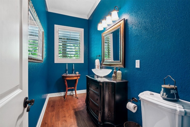 bathroom featuring vanity, toilet, baseboards, wood finished floors, and ornamental molding
