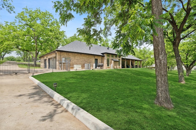 back of property with fence, brick siding, a gate, a lawn, and driveway