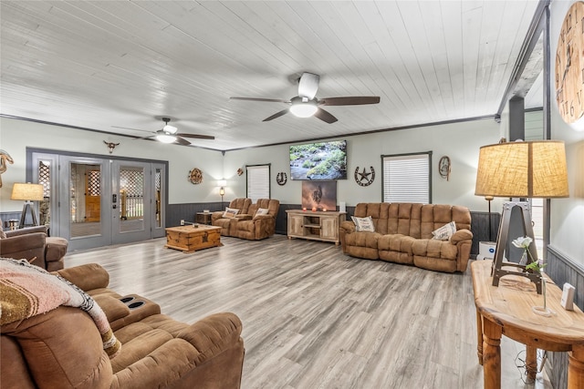 living room featuring french doors, a ceiling fan, a wainscoted wall, and light wood-style floors