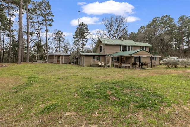 rear view of house featuring a lawn, a patio, and metal roof