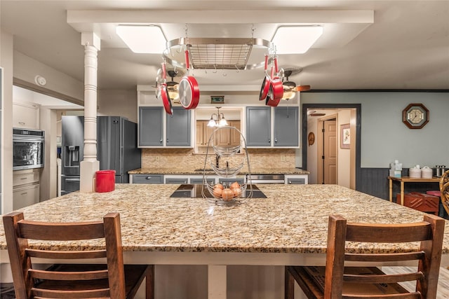 kitchen with a kitchen bar, backsplash, appliances with stainless steel finishes, and gray cabinetry