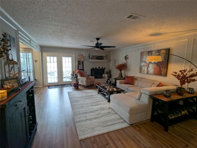 living room featuring a fireplace, dark hardwood / wood-style flooring, ceiling fan, crown molding, and a textured ceiling