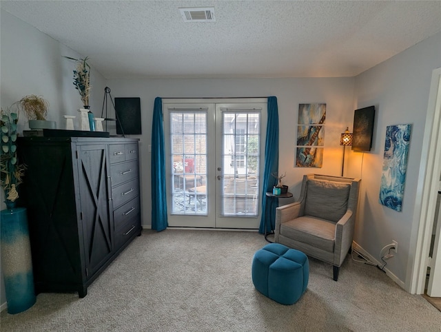 sitting room with light carpet, a textured ceiling, and french doors