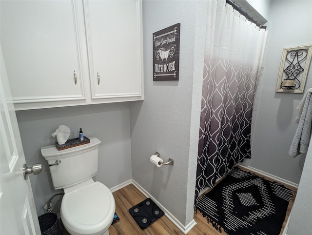 bathroom with hardwood / wood-style floors, a shower with shower curtain, and toilet