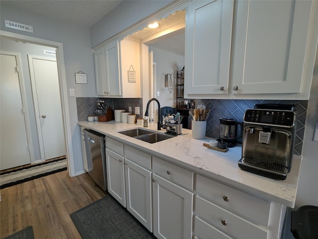 kitchen featuring sink, white cabinetry, a textured ceiling, light wood-type flooring, and dishwasher