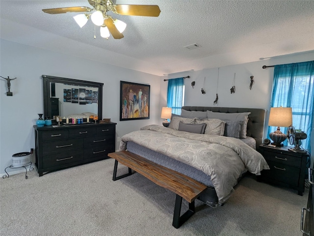 carpeted bedroom featuring a textured ceiling and ceiling fan