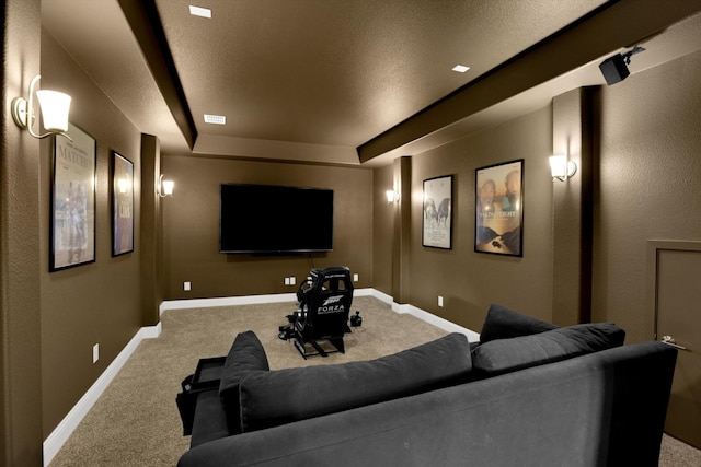 carpeted home theater room featuring track lighting and a raised ceiling