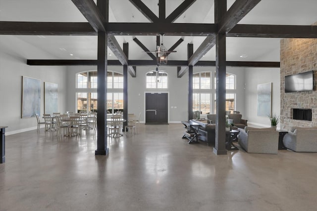 living room featuring a high ceiling, ceiling fan, a fireplace, and beam ceiling