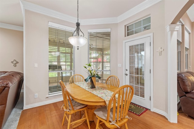 dining space with decorative columns, crown molding, and light wood-type flooring