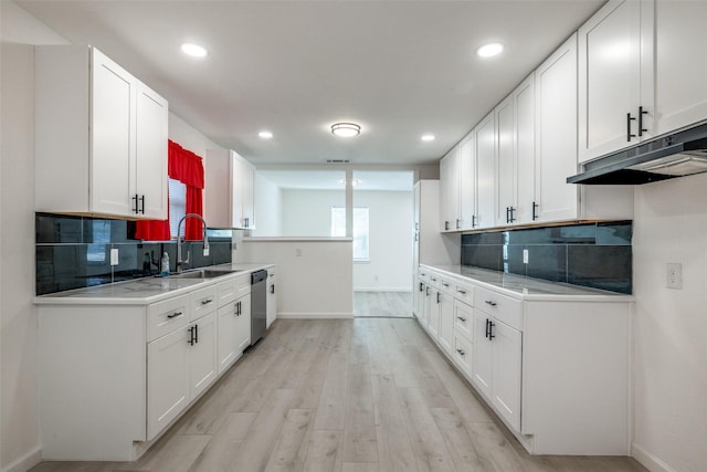 kitchen with tasteful backsplash, sink, white cabinets, stainless steel dishwasher, and light wood-type flooring