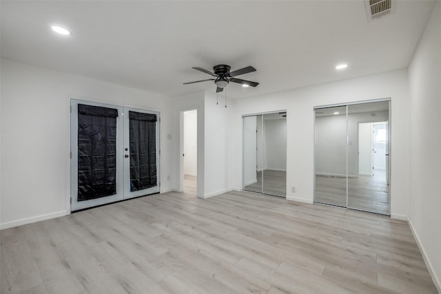 unfurnished bedroom with two closets, light hardwood / wood-style floors, french doors, and ceiling fan