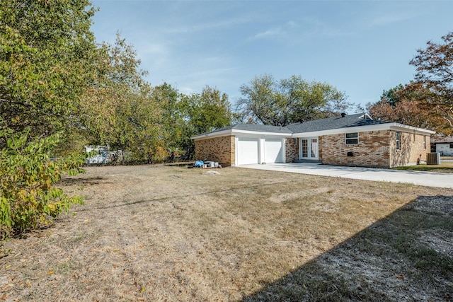 view of side of property featuring french doors, a garage, a yard, and central AC unit