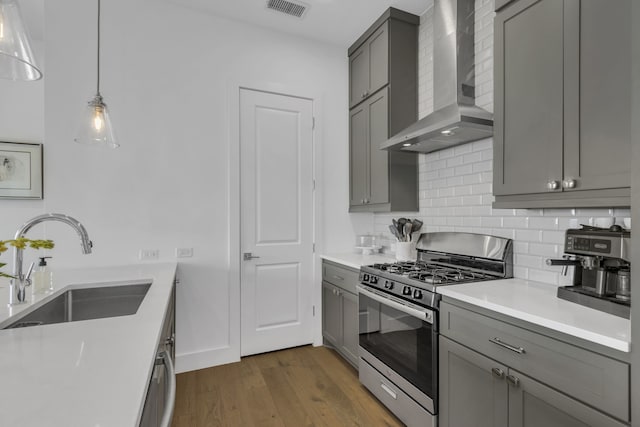 2125 Bird St, Fort Worth, TX 76111 - kitchen featuring appliances with stainless steel finishes, wall chimney range hood, gray cabinetry, backsplash, and dark wood-style floors
