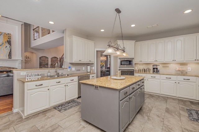 kitchen featuring gray cabinets, a kitchen island, pendant lighting, white cabinetry, and sink