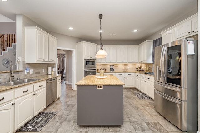 kitchen featuring a kitchen island, appliances with stainless steel finishes, sink, white cabinets, and hanging light fixtures