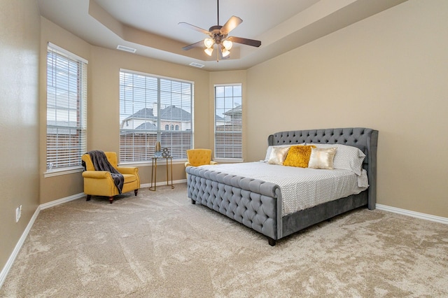 bedroom featuring a raised ceiling, ceiling fan, and carpet