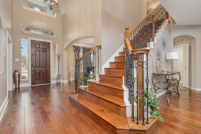 foyer entrance featuring a towering ceiling and wood-type flooring