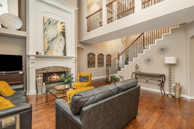 living room with dark hardwood / wood-style flooring, a fireplace, and a high ceiling