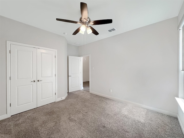 unfurnished bedroom with light colored carpet, ceiling fan, and a closet