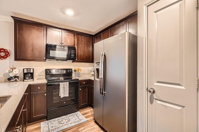 kitchen with light stone countertops, dark brown cabinets, black appliances, and light wood-type flooring