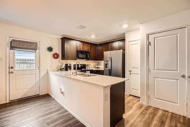 kitchen with sink, stainless steel fridge, dark brown cabinets, range with electric cooktop, and kitchen peninsula