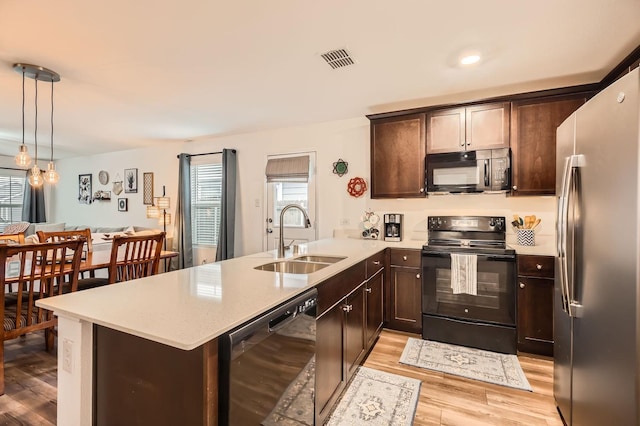 kitchen featuring pendant lighting, sink, black appliances, light hardwood / wood-style floors, and kitchen peninsula