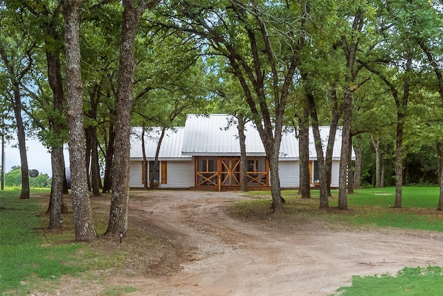 view of front facade with dirt driveway and metal roof