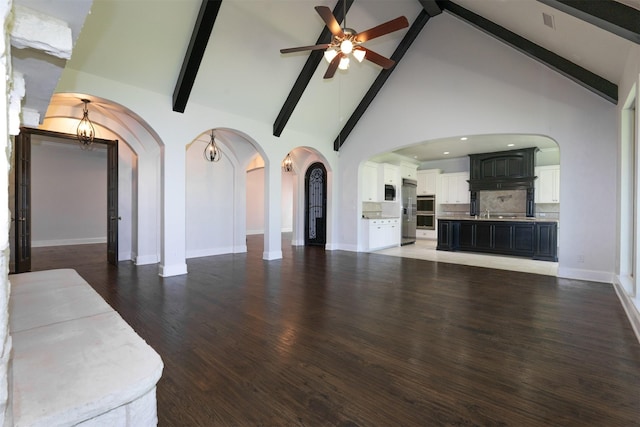 3019 Haywick, The Colony, TX 75056 - unfurnished living room featuring arched walkways, ceiling fan, beamed ceiling, high vaulted ceiling, and wood finished floors