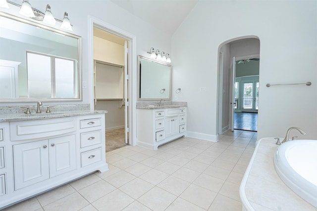 3019 Haywick, The Colony, TX 75056 - bathroom featuring lofted ceiling, two vanities, tile patterned floors, a garden tub, and baseboards