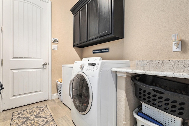 laundry area with washing machine and dryer, cabinets, and light wood-type flooring