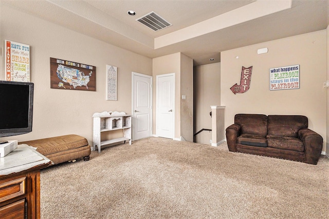 sitting room with carpet floors and a tray ceiling