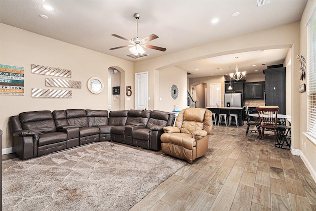 living room with wood-type flooring and ceiling fan with notable chandelier