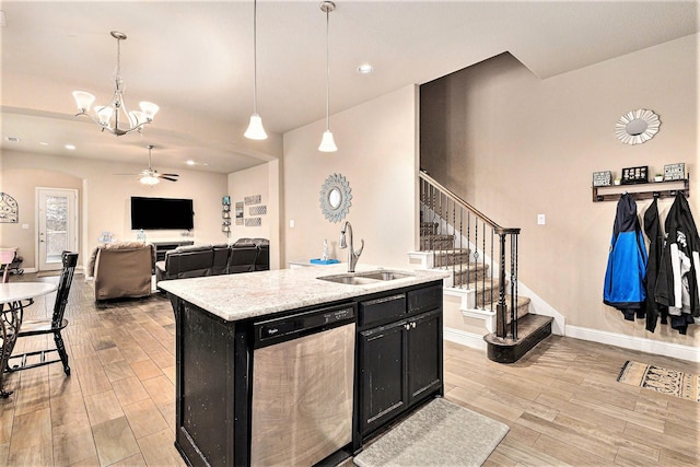 kitchen with sink, light wood-type flooring, stainless steel dishwasher, pendant lighting, and a kitchen island with sink