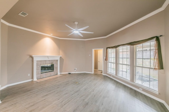 unfurnished living room with light wood-type flooring, crown molding, visible vents, and a tiled fireplace