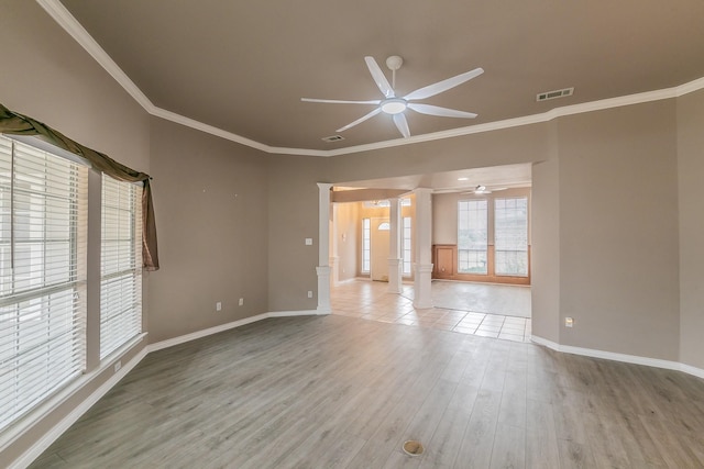 empty room featuring visible vents, light wood-style flooring, ceiling fan, ornamental molding, and ornate columns