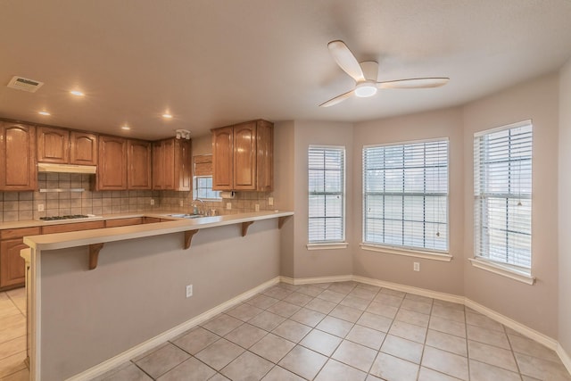 kitchen with light countertops, gas cooktop, visible vents, and a kitchen breakfast bar