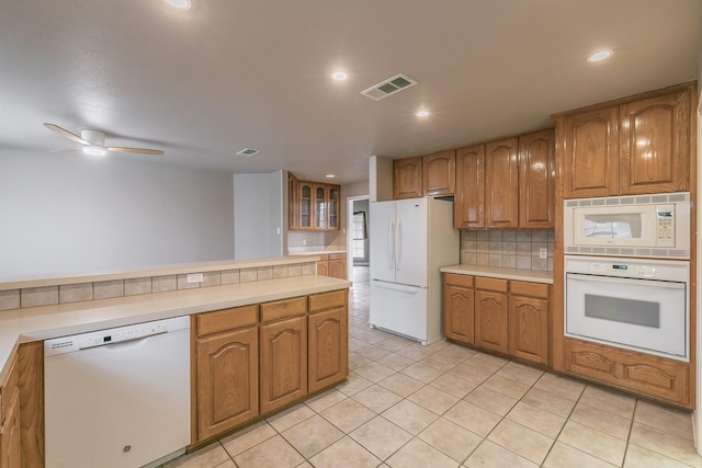 kitchen featuring white appliances, glass insert cabinets, brown cabinets, light countertops, and backsplash