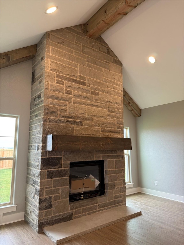 interior details with a stone fireplace, hardwood / wood-style floors, and beam ceiling