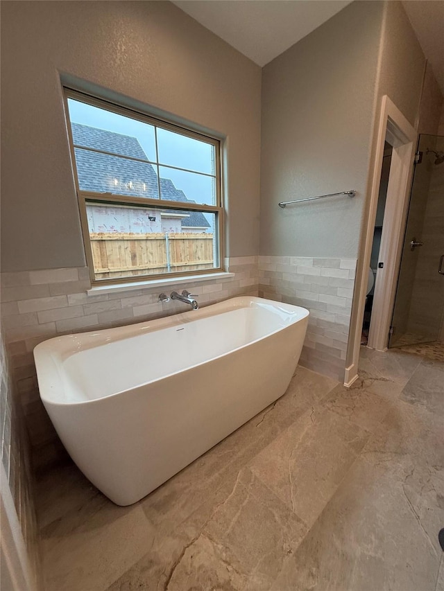 bathroom with tile walls, plus walk in shower, and toilet